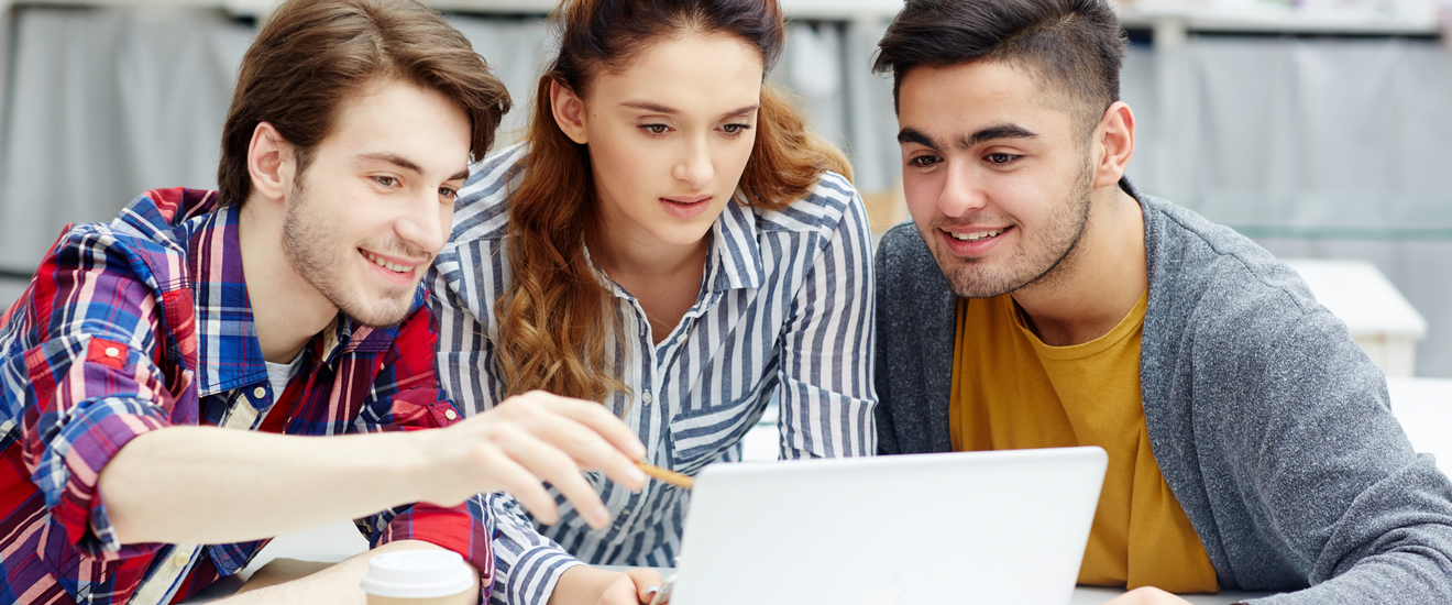 Zwei junge Männer und eine junge Frau blicken interessiert auf einen Laptop