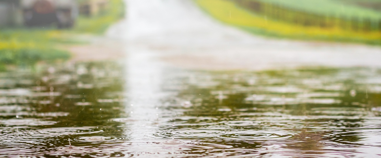 Detailansicht einer wasserüberfluteten Straße auf die Regentropfen fallen