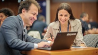 Zwei lächelnde Personen vor einem Laptop am Connect Day