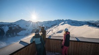 Drei Personen betrachten auf einer Terrasse stehend die Berge