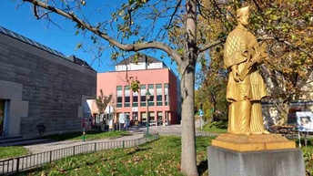 Bildungshaus Kardinal König von außen mit Denkmal im Vordergrund