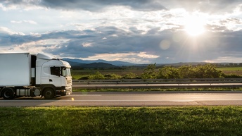 LKW fährt auf einer Straße neben idyllischer Landschaft