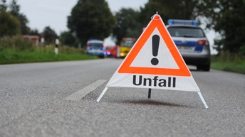 Warndreieck mit Schriftzug Unfall steht auf einem Fahrstreifen, dahinter stehen weitere Einsatzfahrzeuge in der Unschärfe