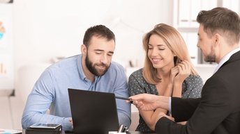 Drei lächelnde Personen im Gespräch auf Laptopbildschirm blickend