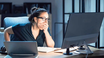 Frau erschrickt beim Blick auf den Bildschirm