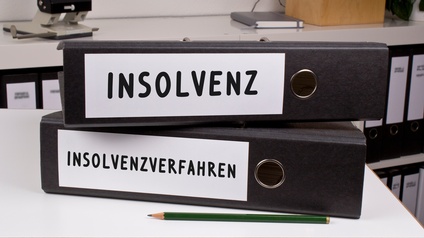 Zwei schwarze Ordner liegen gestapelt auf einer hellen Unterfläche. Auf dem Rücken des oberen Ordners steht Insolvenz. Auf dem Rücken des unteren Ordners steht Insolvenzverfahren