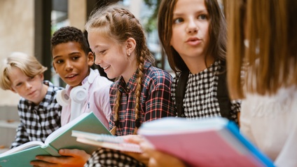 Kinde nebeneinandersitzend im Gespräch mit Büchern am Schoß