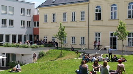 Menschen sitzen vor dem KK Haus in der Wiese