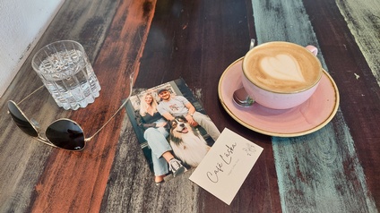 Wasserglas, Kaffeetasse mit Kaffee und eine Postkarte und Visitenkarte des Café Laska