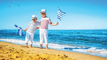 Zwei Kinder mit Griechenland-Fahnen am Strand