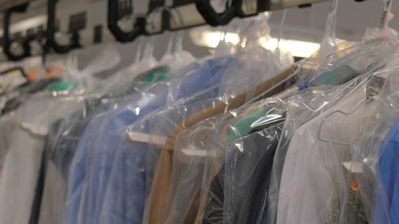 Frisch gewaschene Kleidung hängt, verpackt in Plastiküberzügen, in der Textilreinigung