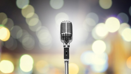 Nahaufnahme eines Vintage-Mikrofons  vor einem gelb-bläulichen Bokeh-Hintergrund