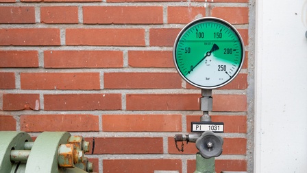 Detailaufnahme von einer Gasspeicheranalage mit Druckmanometer vor einer roten Ziegelwand