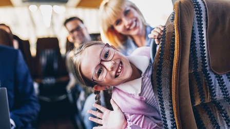 Ein Kind sitzt in einem Reisebus und winkt