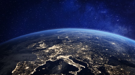 Satellitenaufnahme Europas bei Nacht mit vielen hellen Punkten, Wölbung der Erde ersichtlich