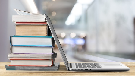 Laptop an buntem Bücherstapel lehnend