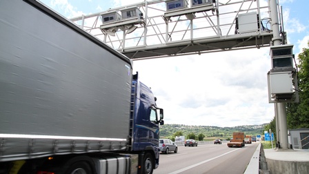 LKW fährt auf einer Autobahn bei einer Maut-Stelle vorbei