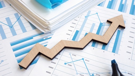 Holzpfeil mit stufigem Verlauf liegt auf Unterlagen mit verschiedenen statistischen Diagrammen