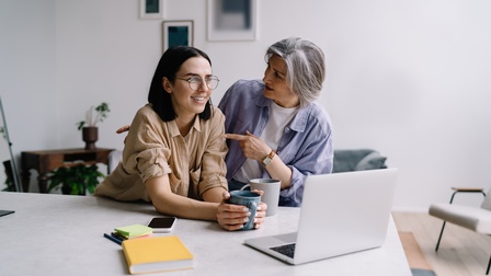 Zwei Generationen Frauen bei Gespräch zu Betriebsübergabe vor Laptop