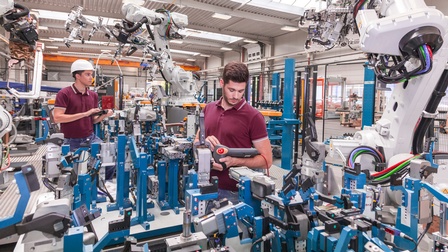 Zwei Personen in Fabrik stehend umgeben von 