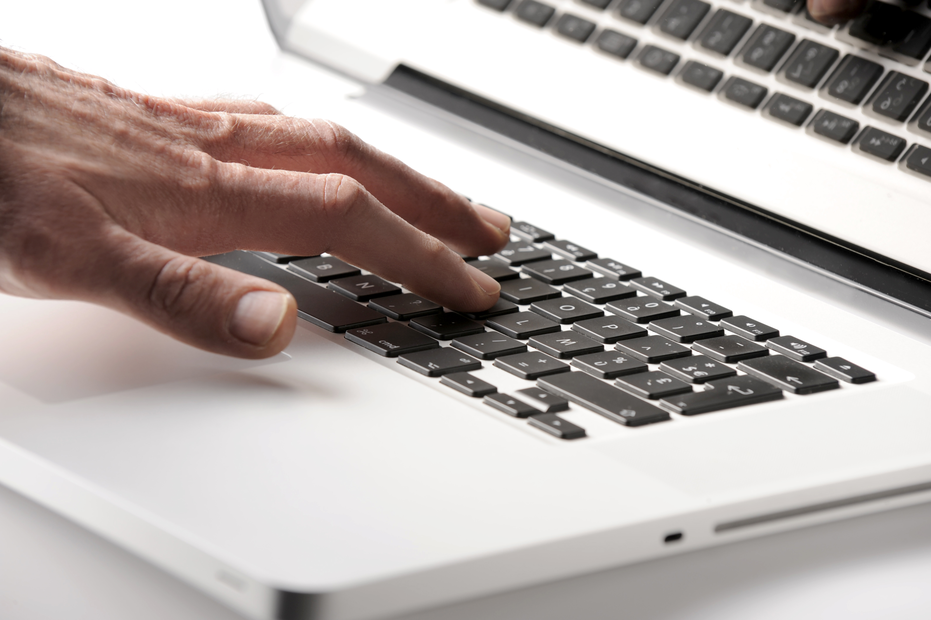 Nahaufnahme der linken Hand einer Person auf der Tastatur eines Laptops