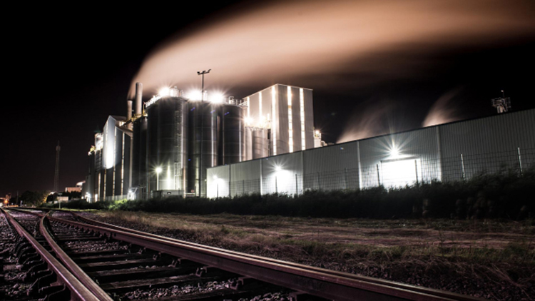 Bahngleise im Vordergrund, im Gas-Raffinerie nachts beleuchtet