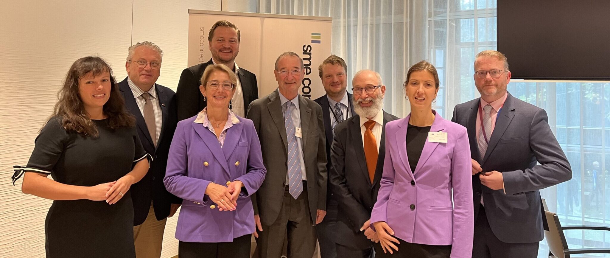 Gruppenbild mehrerer lächelnder Personen, die nebeneinander stehen