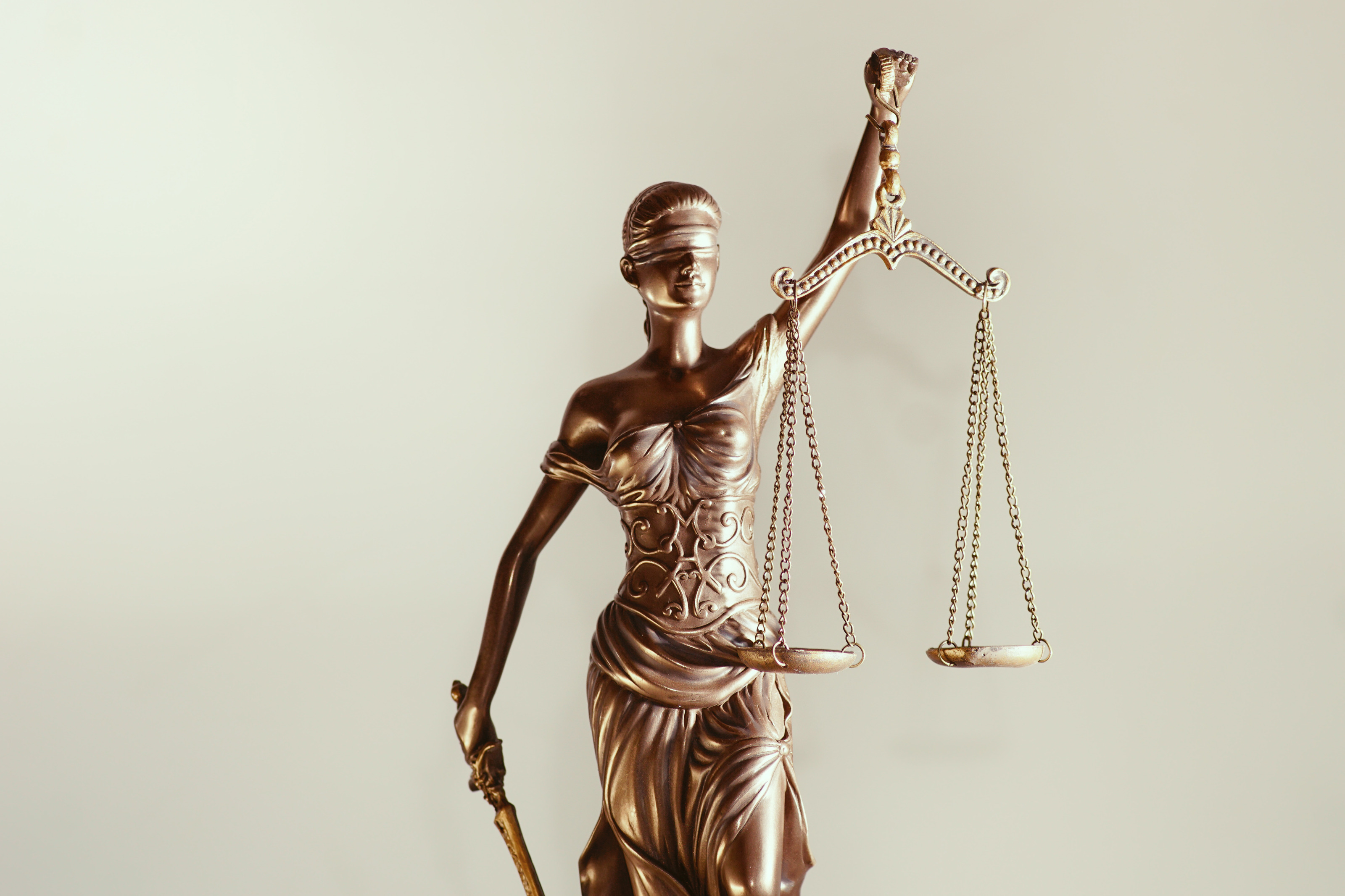 Justitia Figur hält mit verbundenen Augen eine Waagschale in der einen Hand und in der anderen ein Schwert, Symbolik des Rechts