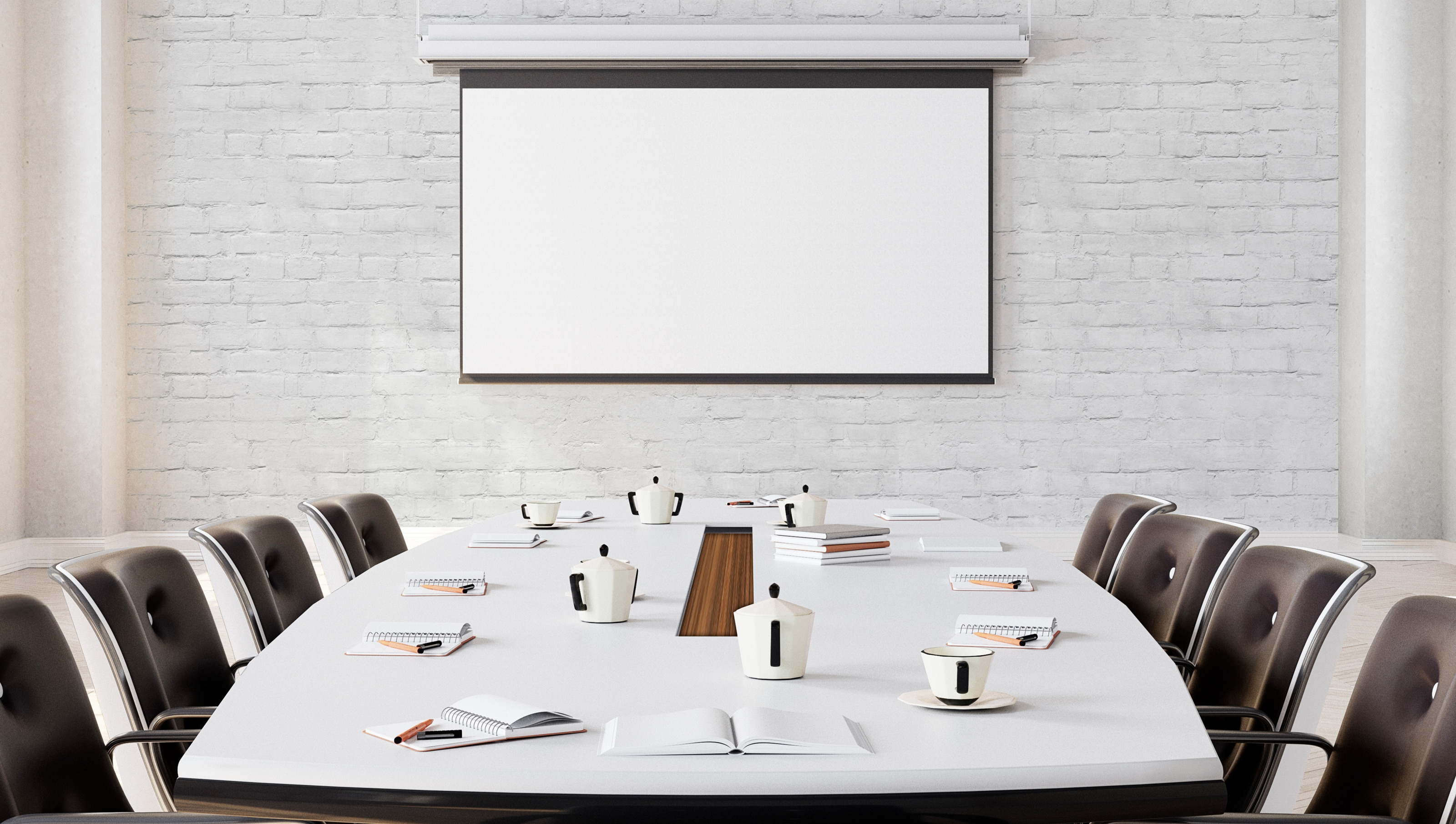 Weißer Besprechungstisch mit acht schwarzen Stühlen, auf dem Kaffeetassen, Kannen und Arbeitsutensilien liegen, im Hintergrund auf weißer Ziegelwand Leinwand hängend