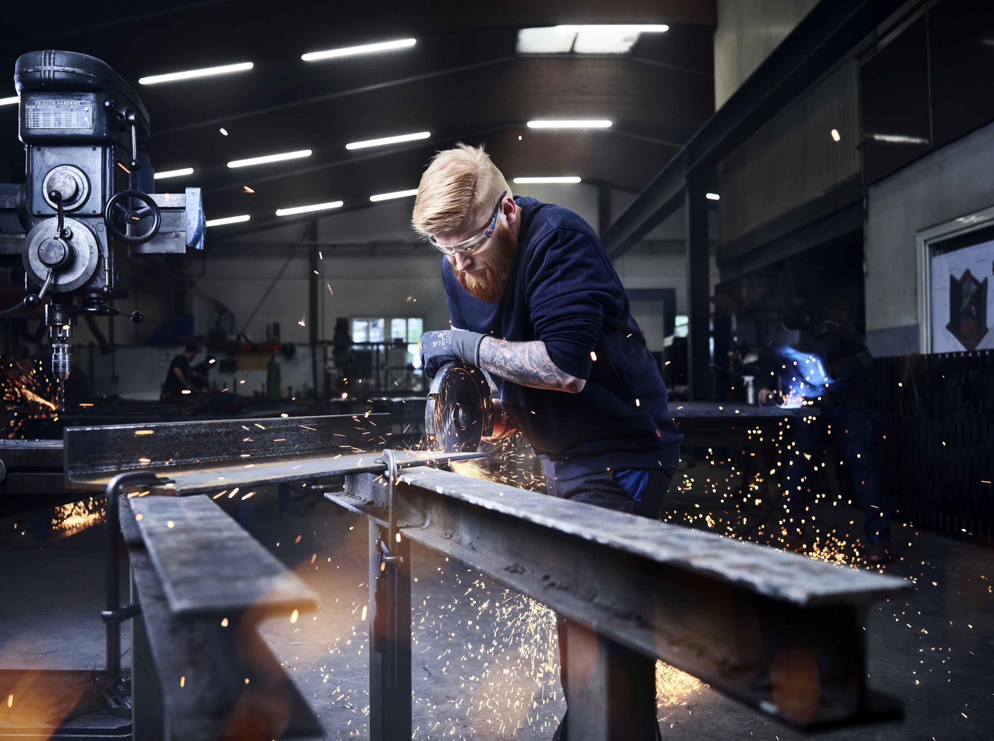 Ein Mann sägt an einem Metallteil, das auf zwei Metallträger gespannt ist