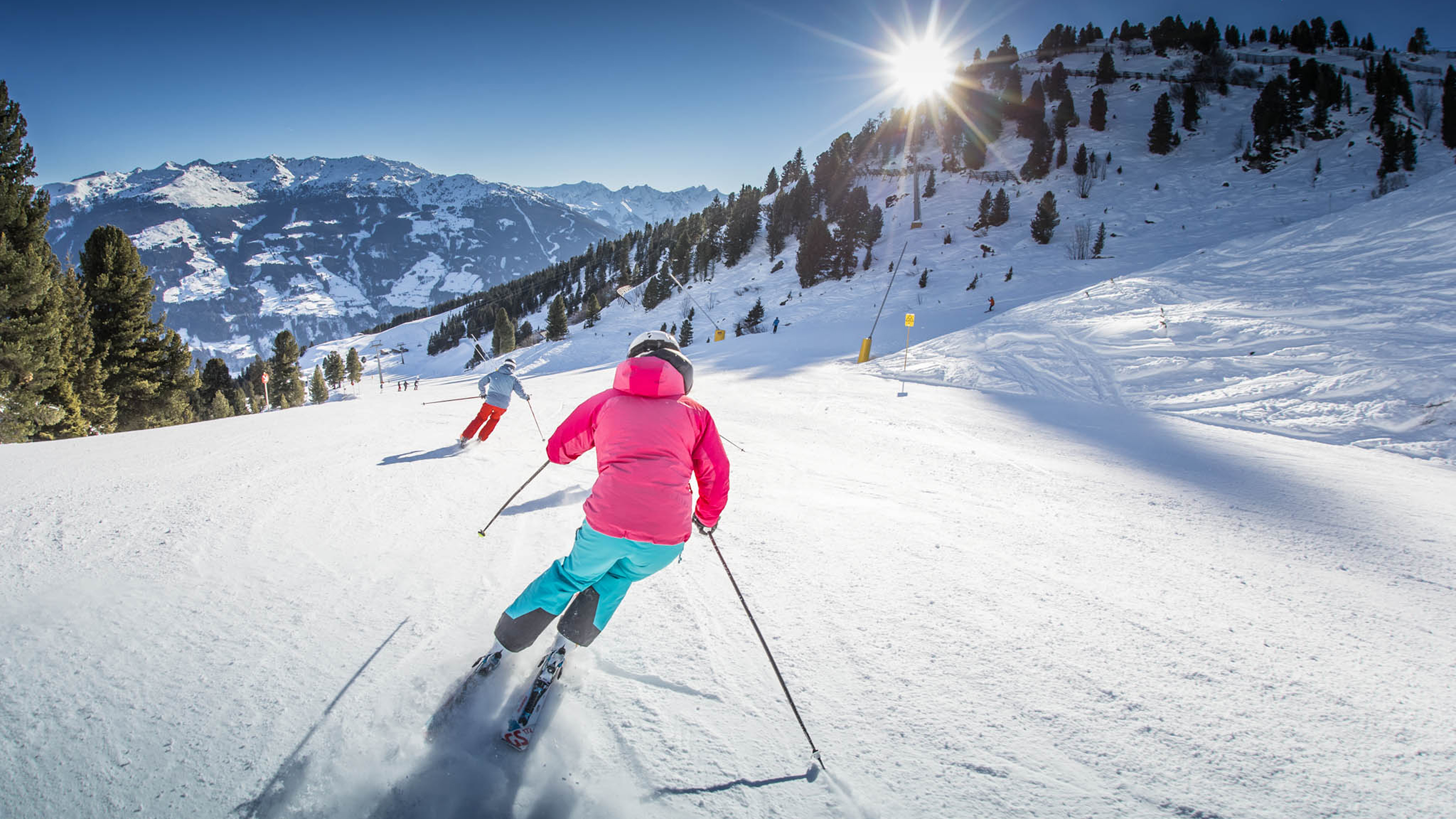 Skifahrende Personen von hinten auf der Schneepiste