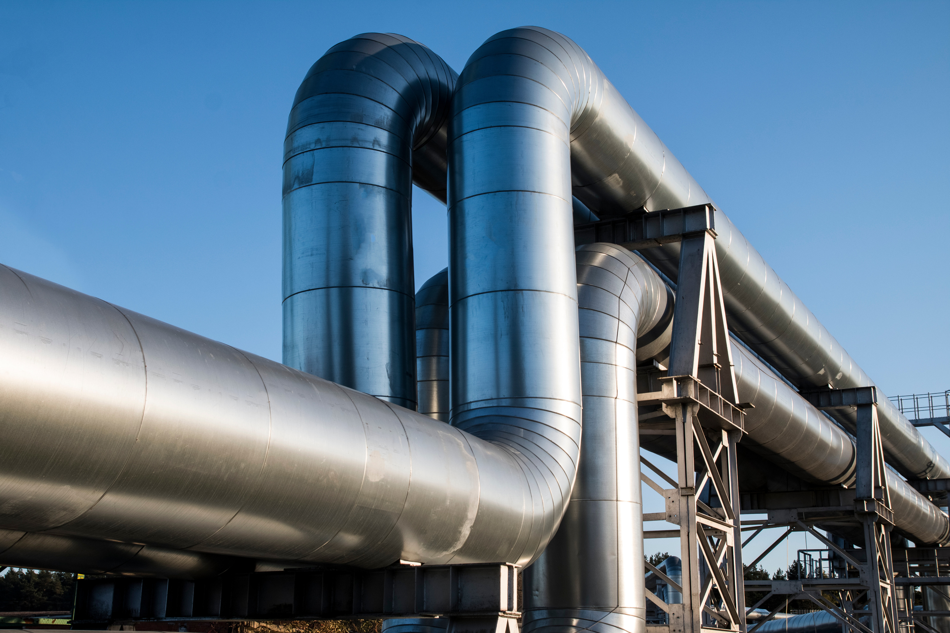 Zwei große Pipelines verlaufen parallel nebeneinander vor blauem Himmel