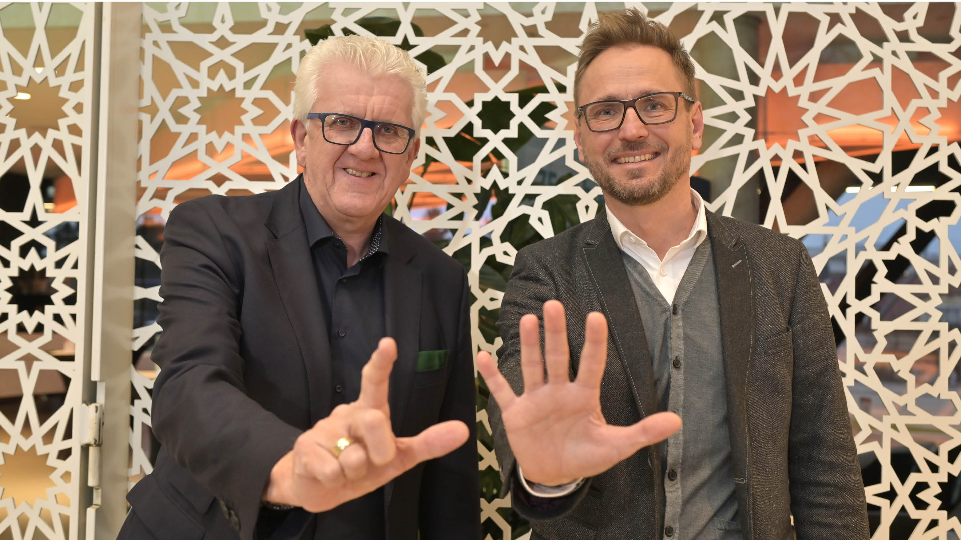 Gollenz und Kern. Gollenz zeigt zwei Finger hoch, Kern fünf – so symbolisieren sie 25 Jahre.