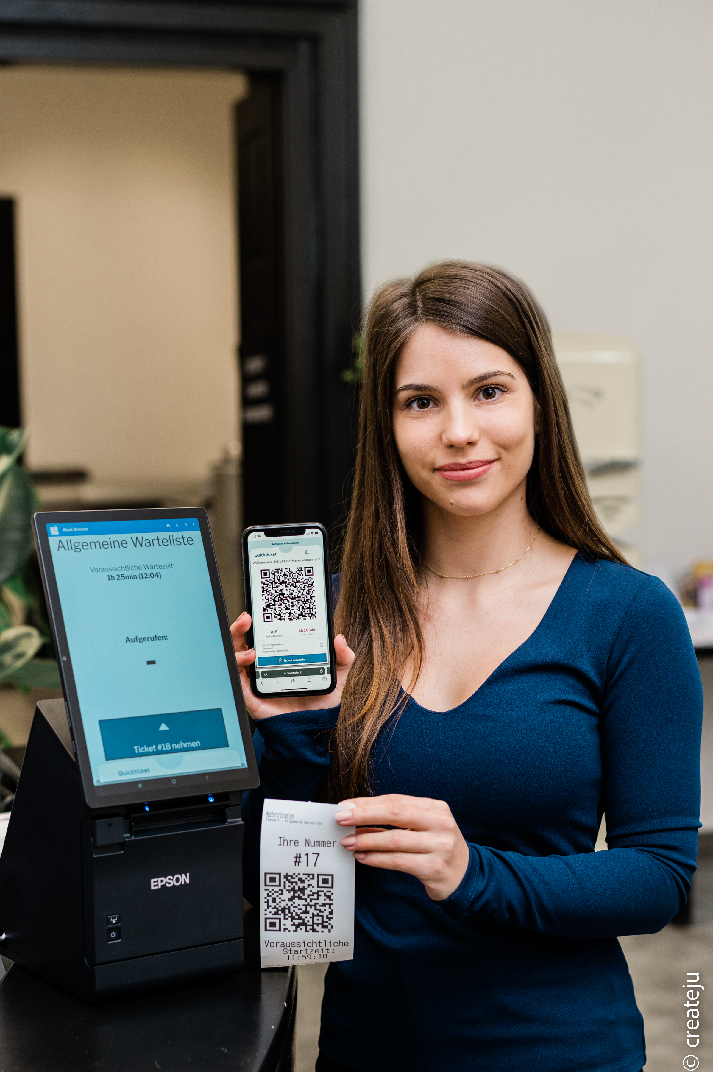 Katharina Feiertag vor einem Tablet und mit einem Handy mit QR-Code in der Hand