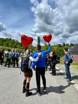 Zwei Wanderer von hinten halten jeweils einen Luftballon in Herzform in der Hand