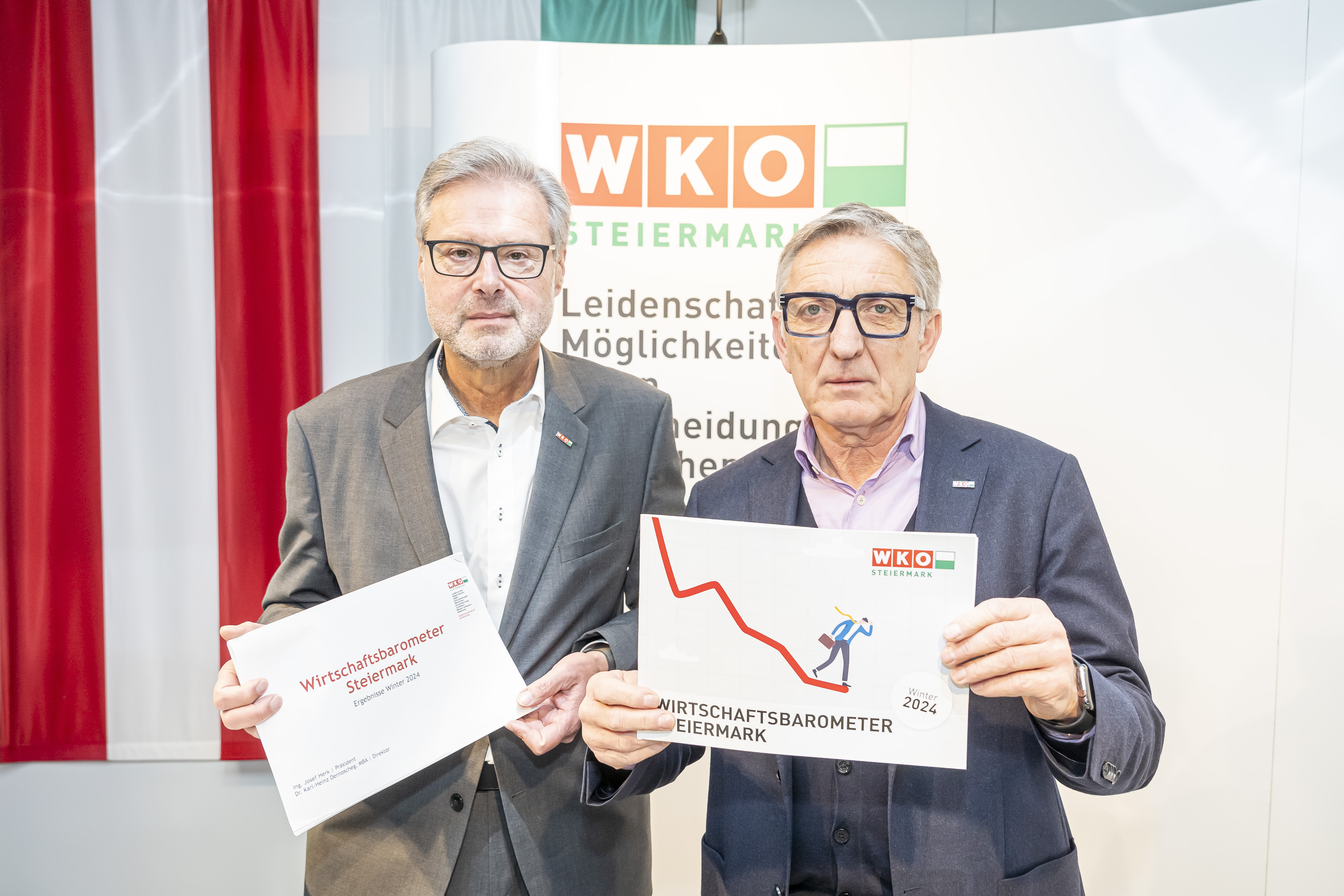 Karl-Heinz Dernoscheg und Josef Herk stehen neben einander und halten Wirtschaftsbarometer-Karten vor sich