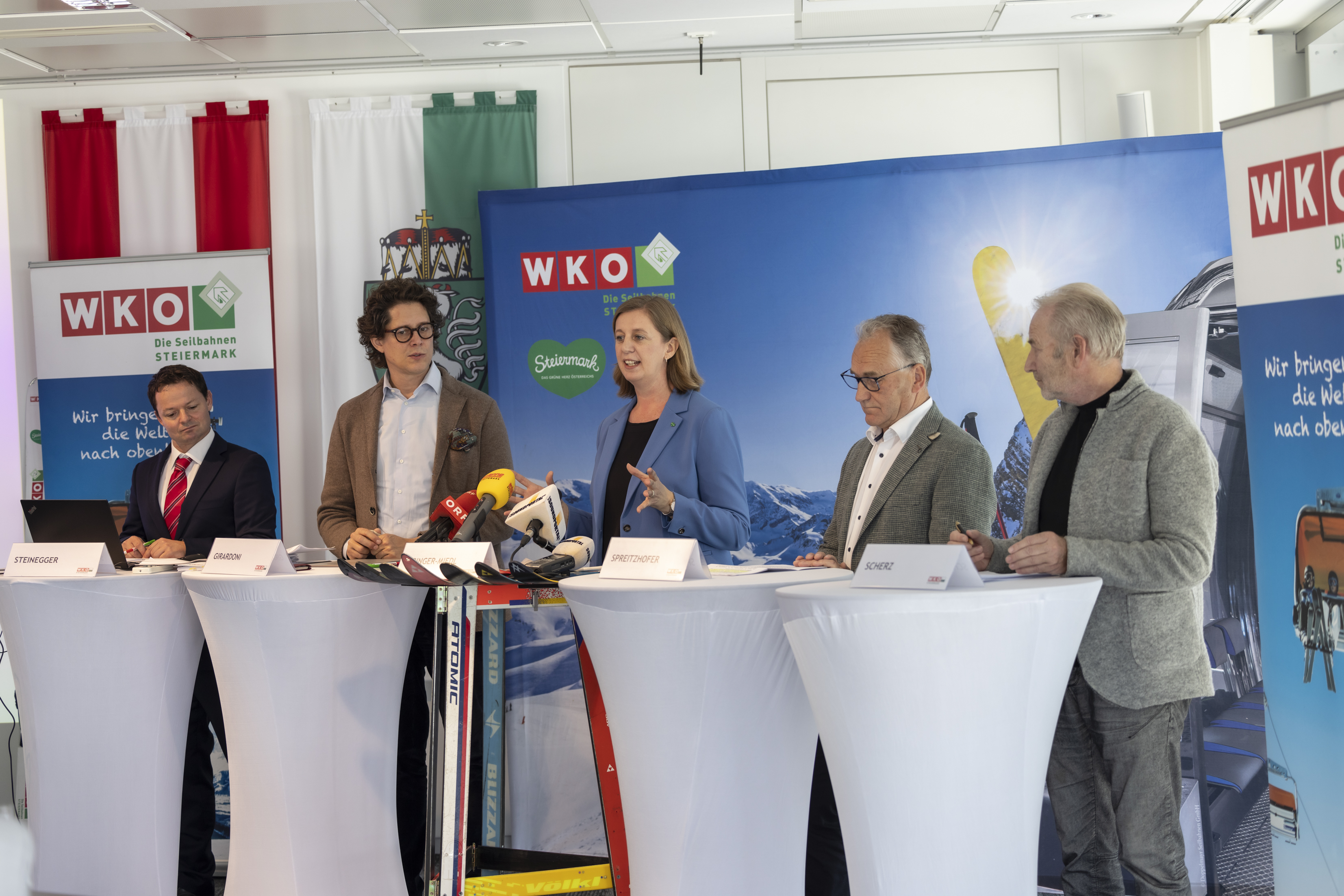 Foto von der Pressekonferenz mit allen Rednern, die hinter Rednerpulten stehen