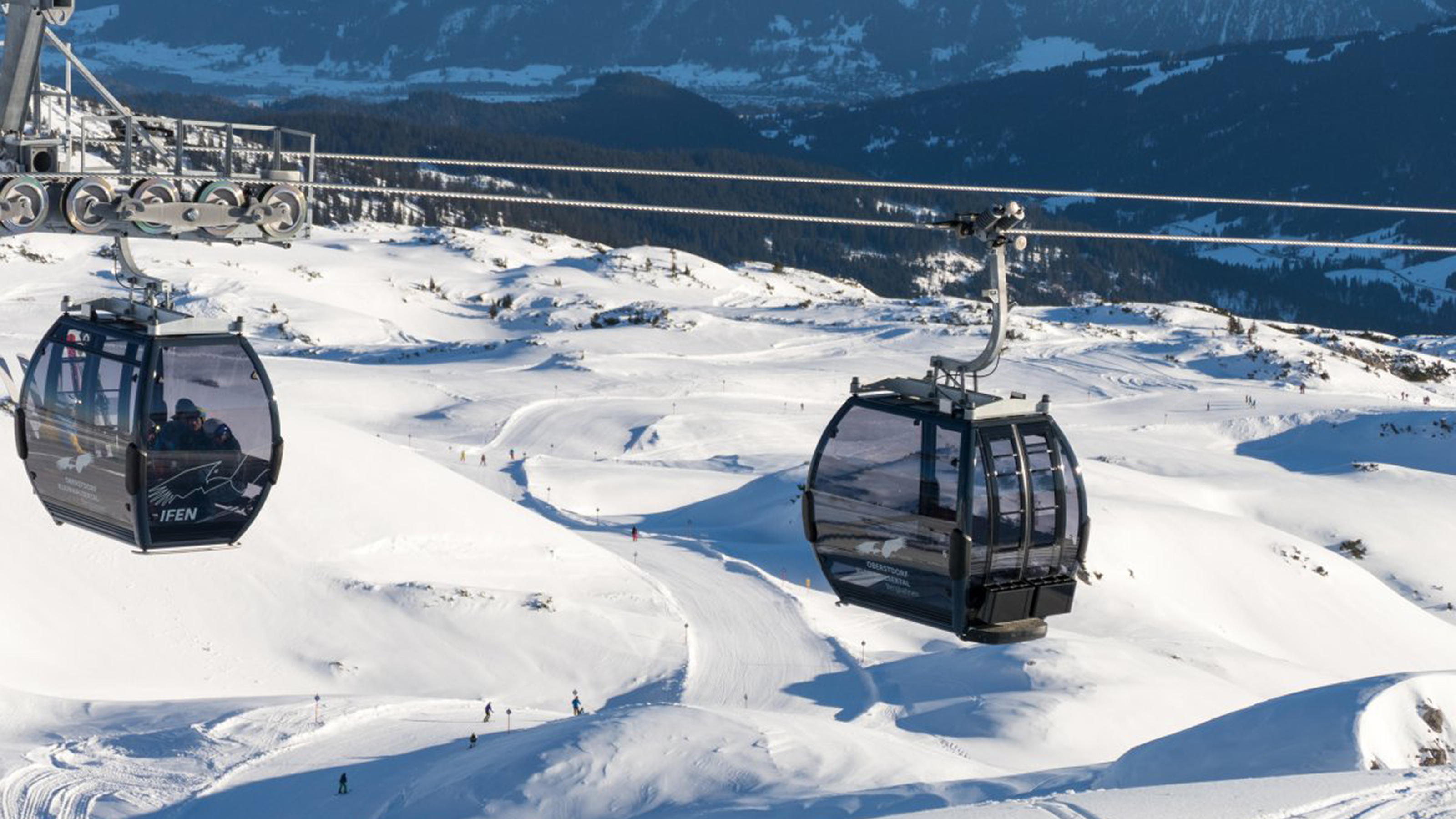 Zwei Seilbahn-Gondeln und Scheepiste