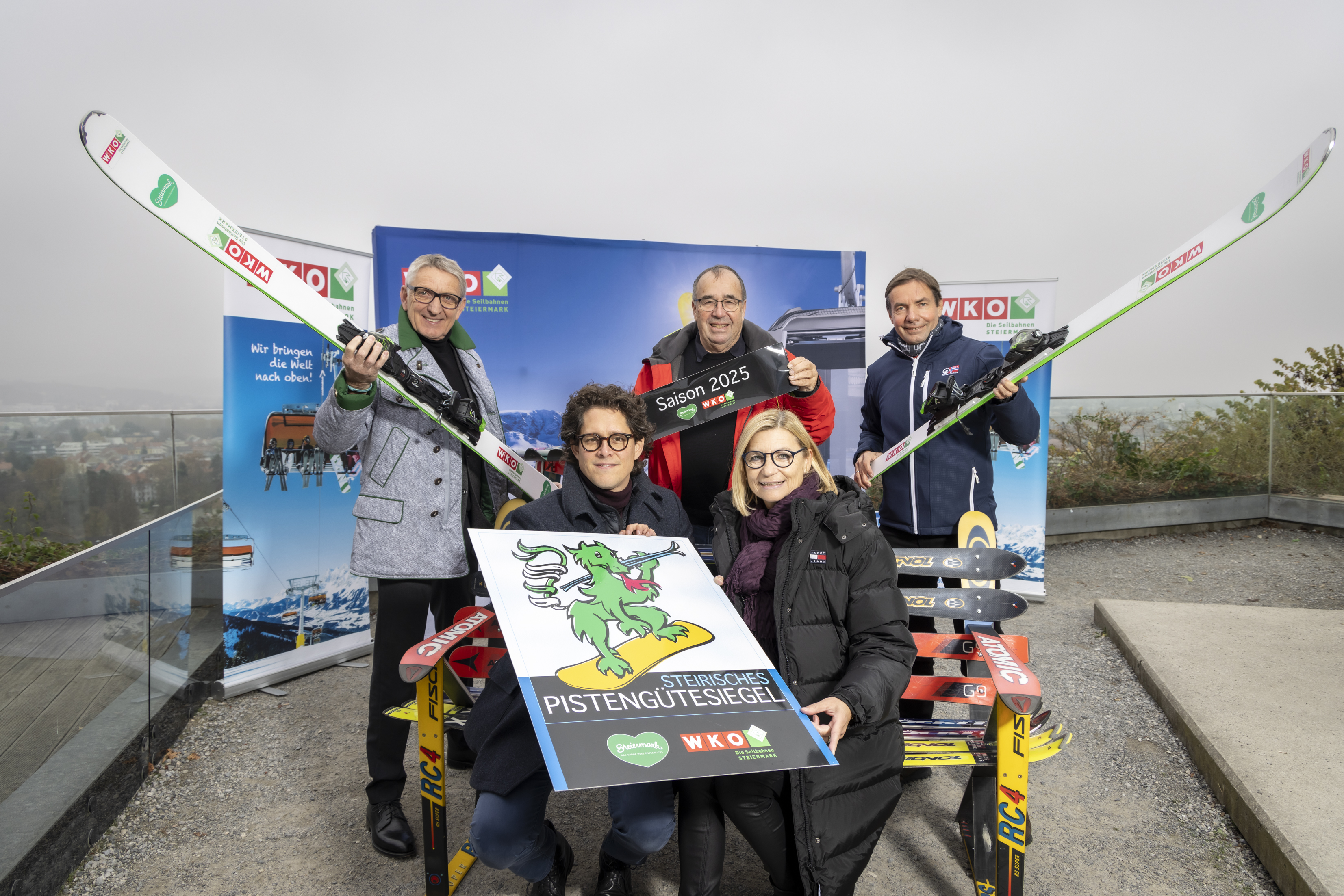 5 Personen posieren mit Schild und Skiern