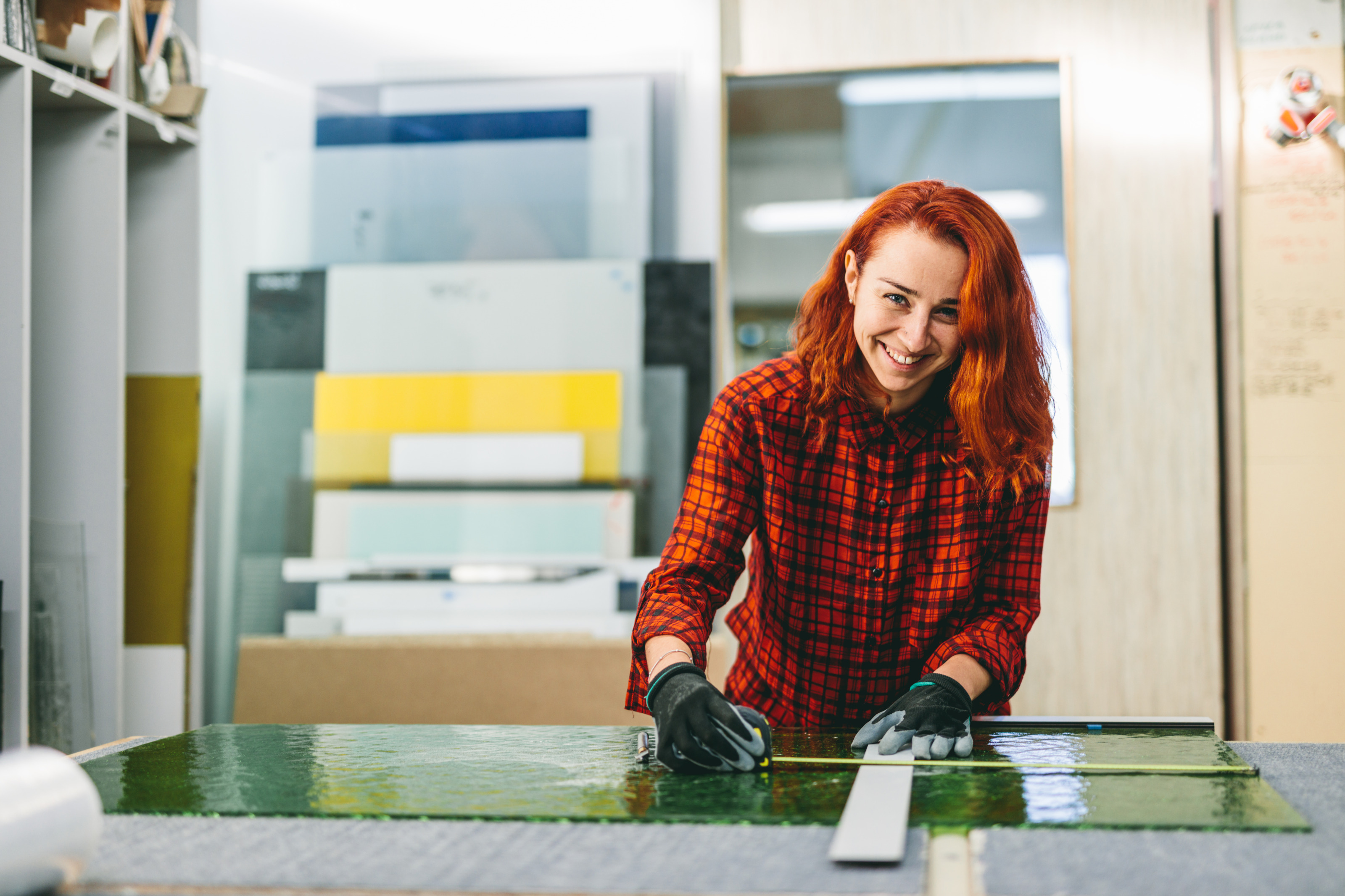 Lehrling lächelnd Glasscheibe auf Werkbank vermessend