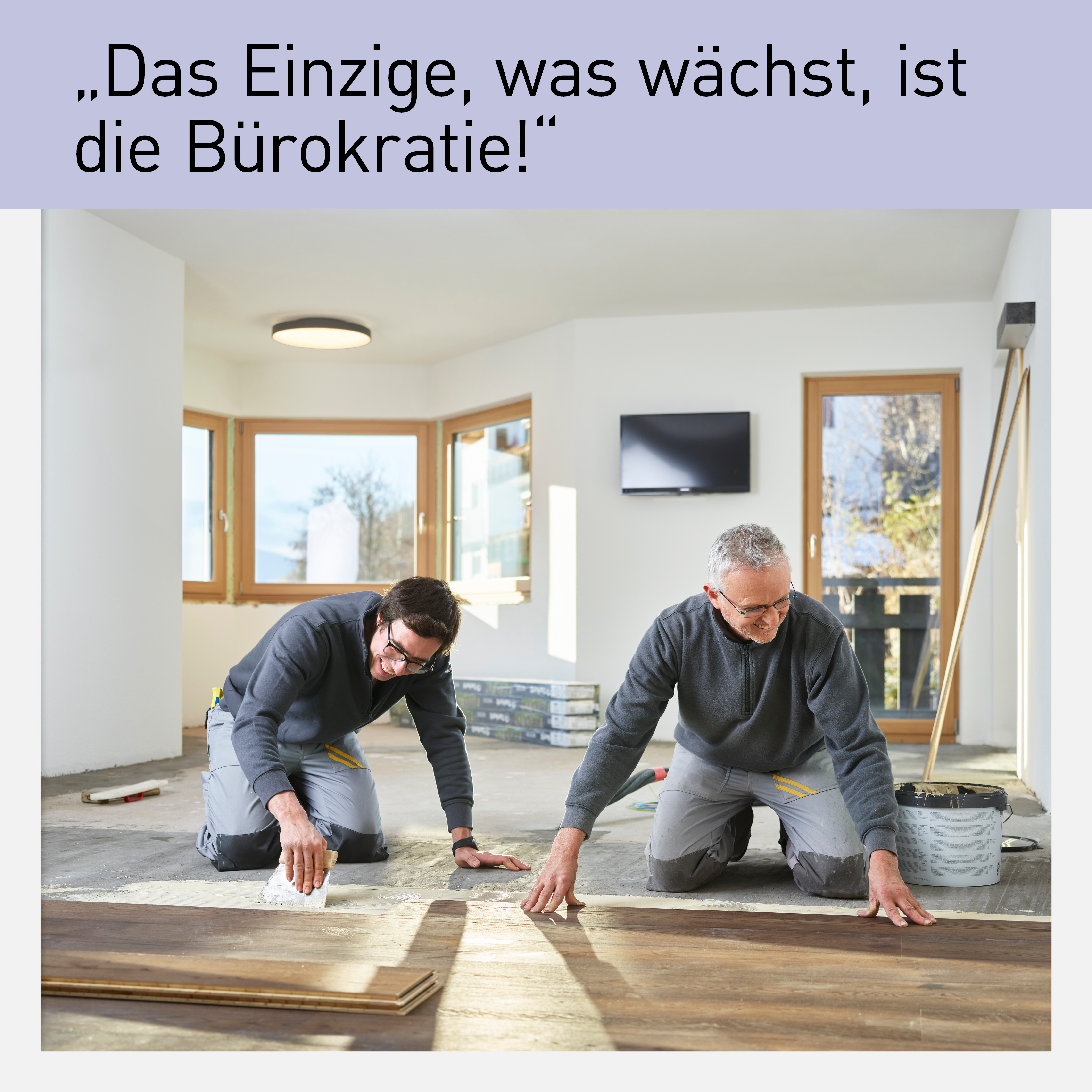 wei Handwerker verlegen Bodenbelag in einem hellen Raum mit großen Fenstern. Das Bild zeigt eine professionelle und konzentrierte Arbeitsatmosphäre. Der Slogan „Das Einzige, was wächst, ist die Bürokratie!“ hebt die Herausforderungen der Bürokratie im Handwerksbereich hervor.