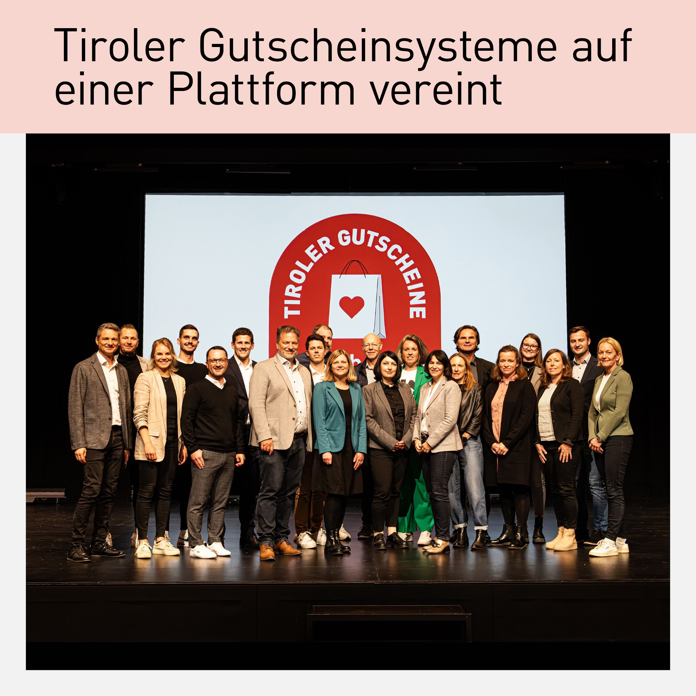 Gruppenfoto der Initiatoren und Partner:innen der Plattform 'Wir schenken regional' vor einer Leinwand mit dem Logo 'Tiroler Gutscheine'. Präsentation der Initiative zur Förderung lokaler Gutscheinsysteme in Tirol, aufgenommen auf einer Bühne