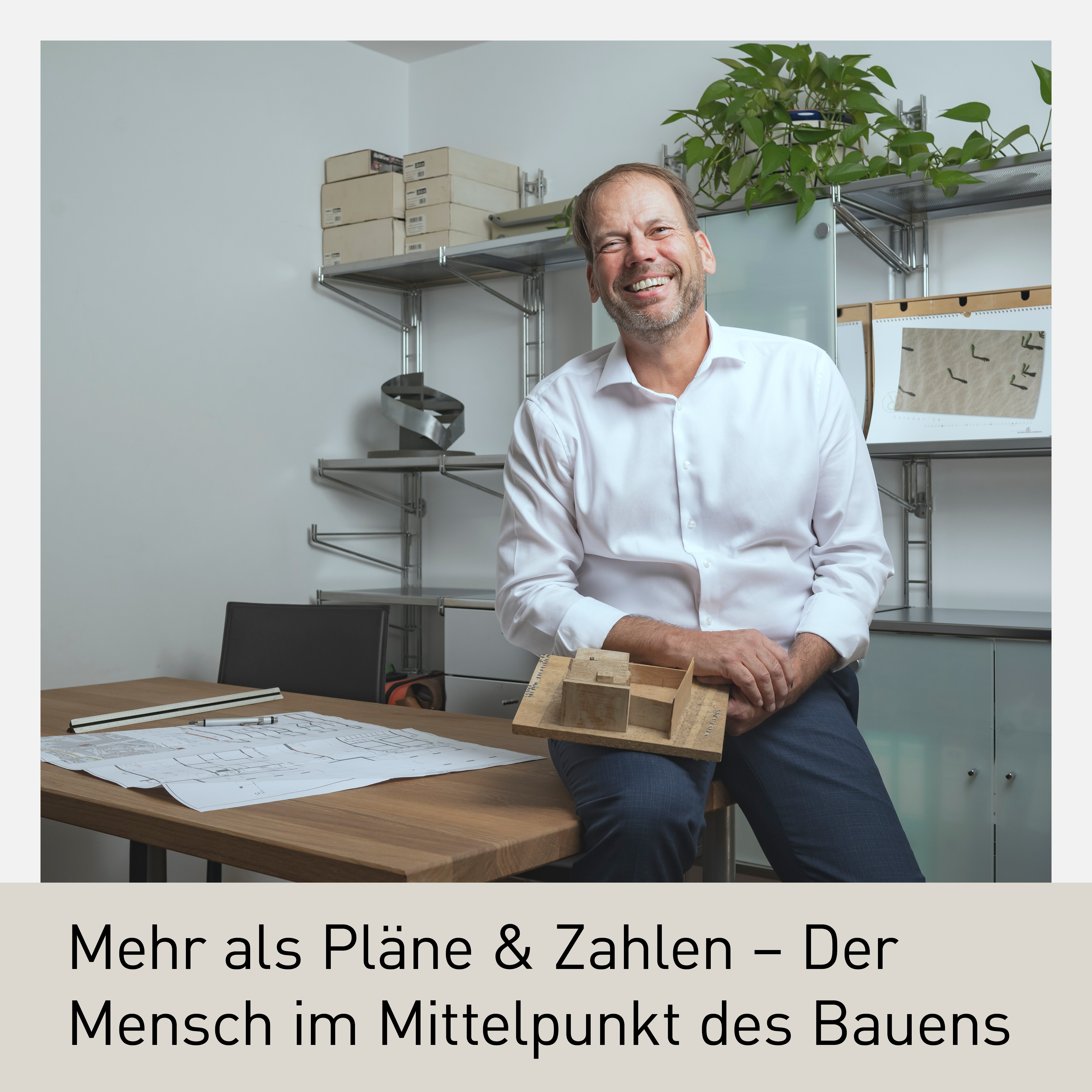 Porträt von Martin Nothdurfter, Fachgruppenobmann der Ingenieurbüros in der Wirtschaftskammer Tirol. Er sitzt entspannt an einem Schreibtisch mit Architekturplänen und einem Holzmodell in der Hand. Im Hintergrund sind Regale mit Arbeitsmaterialien zu sehen. Die Szene vermittelt Fachkompetenz, Leidenschaft für den Hochbau und den Fokus auf den Menschen im Bauwesen.