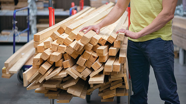 Mann mit einem Einkaufswagen vollbeladen mit Holzleisten