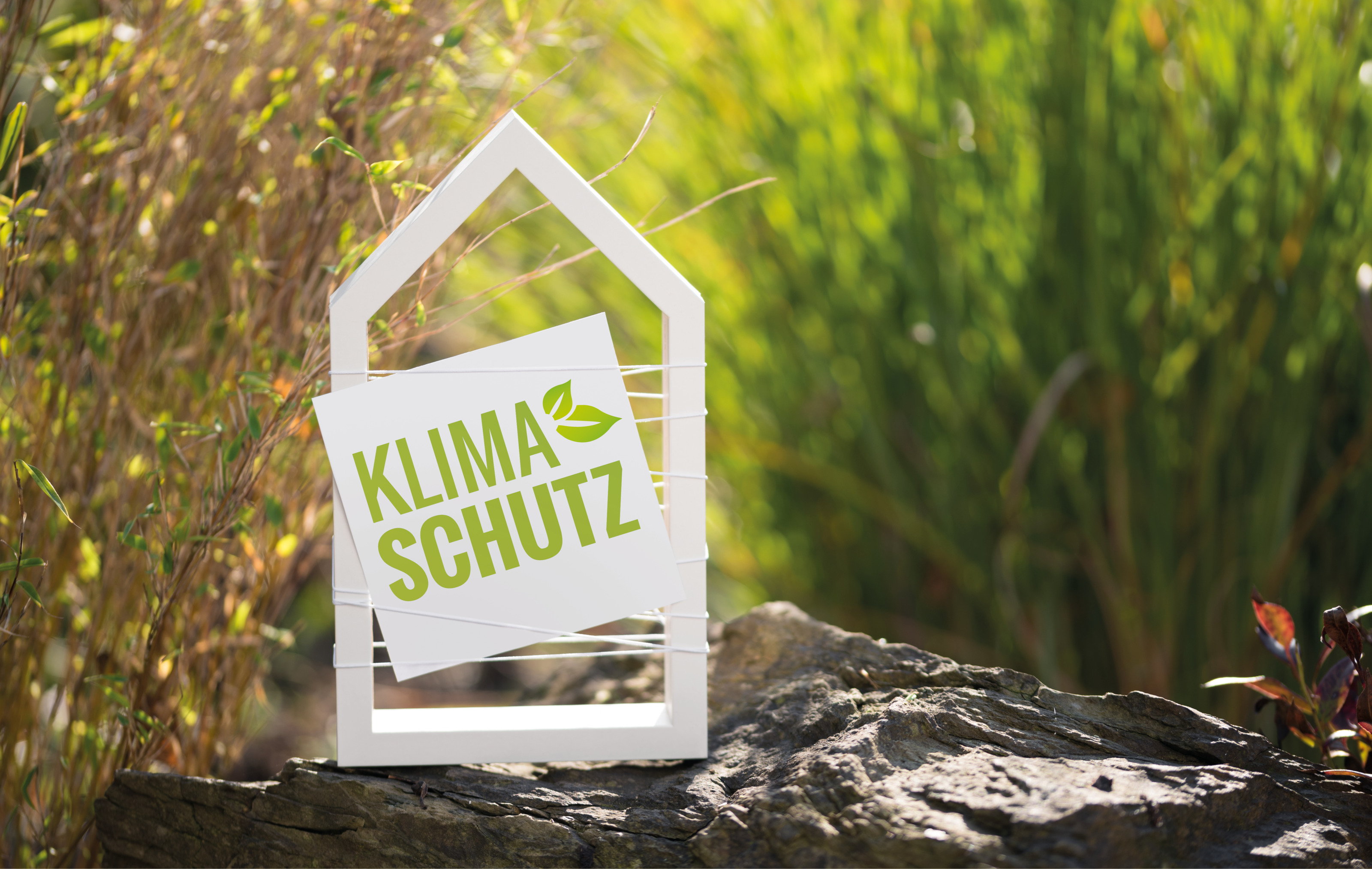 Weißes Haus vor natürlichen Hintergrund mit Schild Klimaschutz