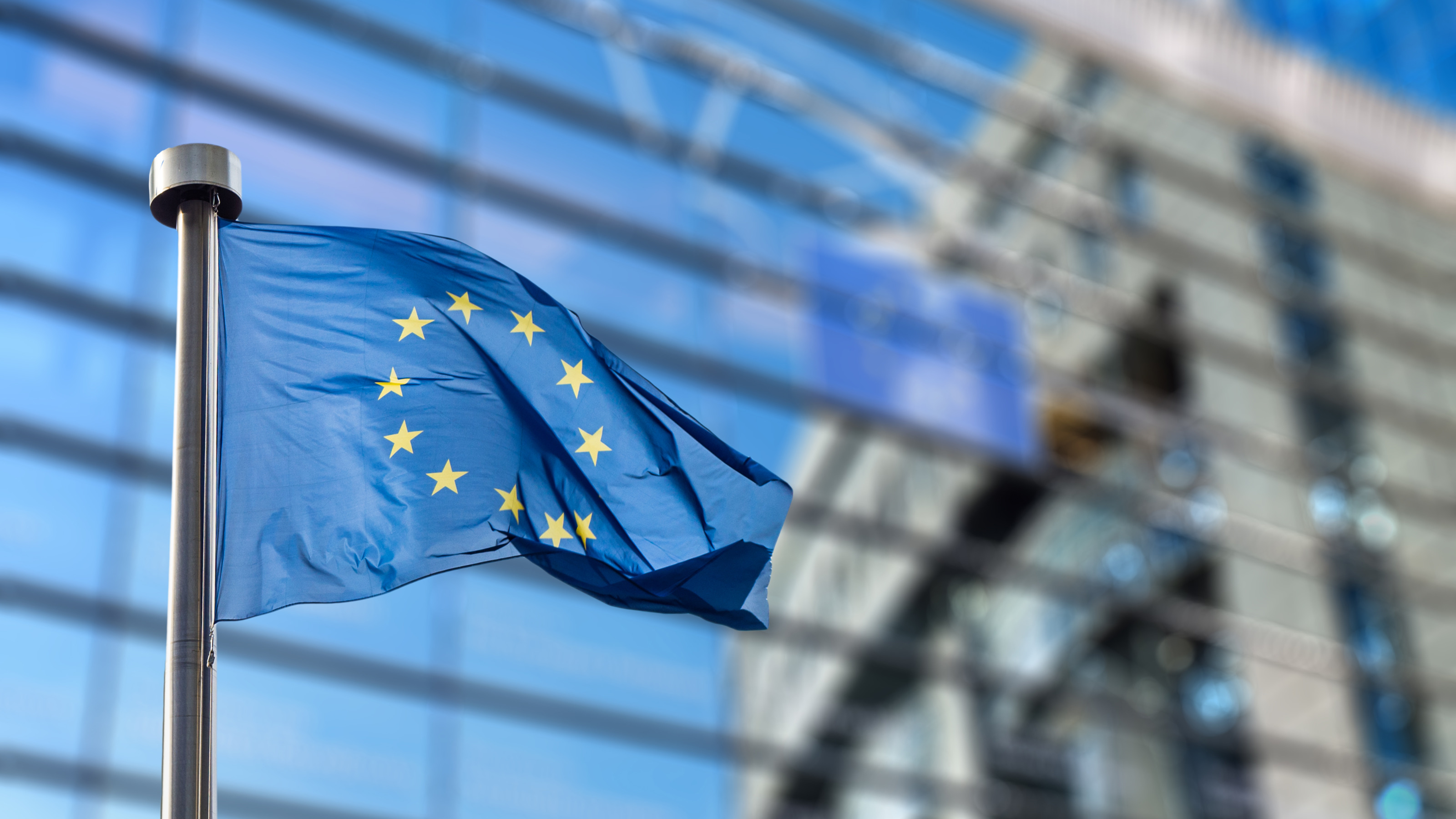 Eu-Flagge im Wind wehen, im Hintergrund Hausfassade