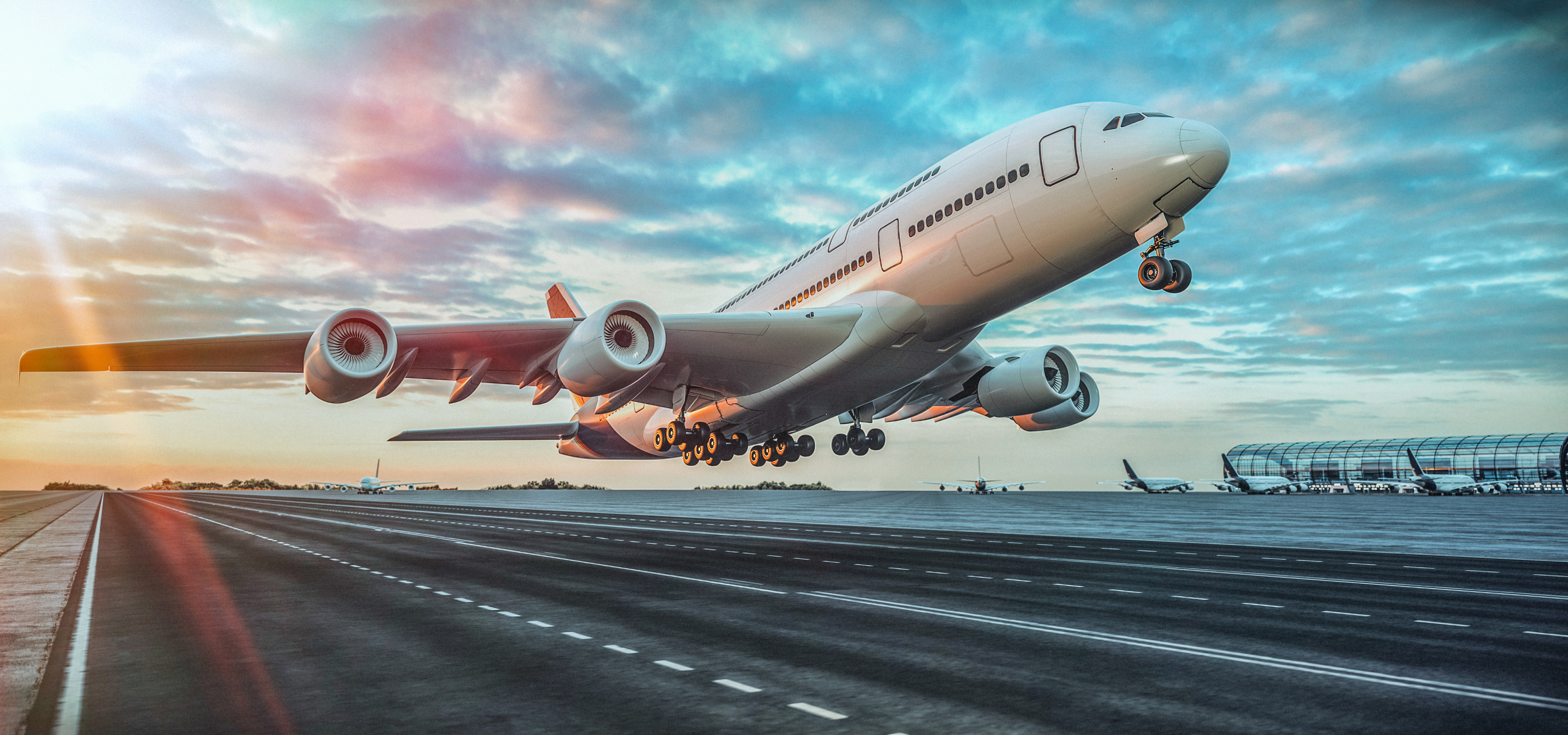 Großes Flugzeug beim Starten auf Landebahn im Licht des Sonnenuntergangs, im Hintergrund weitere Flugzeuge parkend