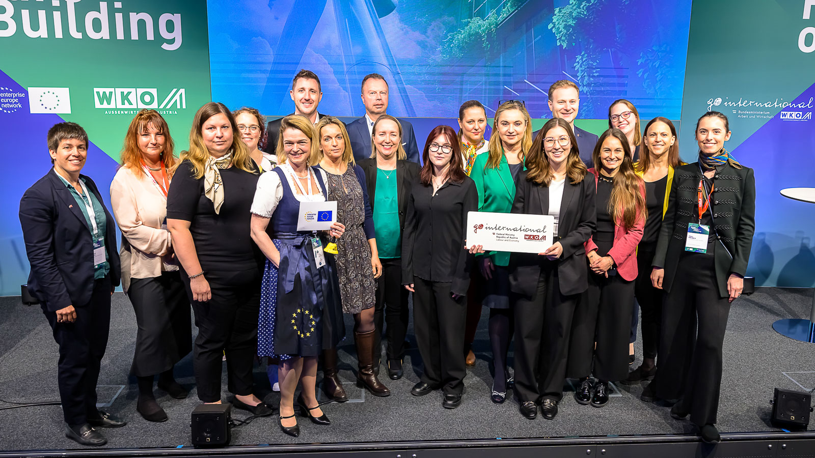 Gruppenbild mehrere Personen neben- und hintereinander vor Wand mit Projektion einer begrünten Hausfassade, Logos und Schriftzügen wie building, wko und go international stehend